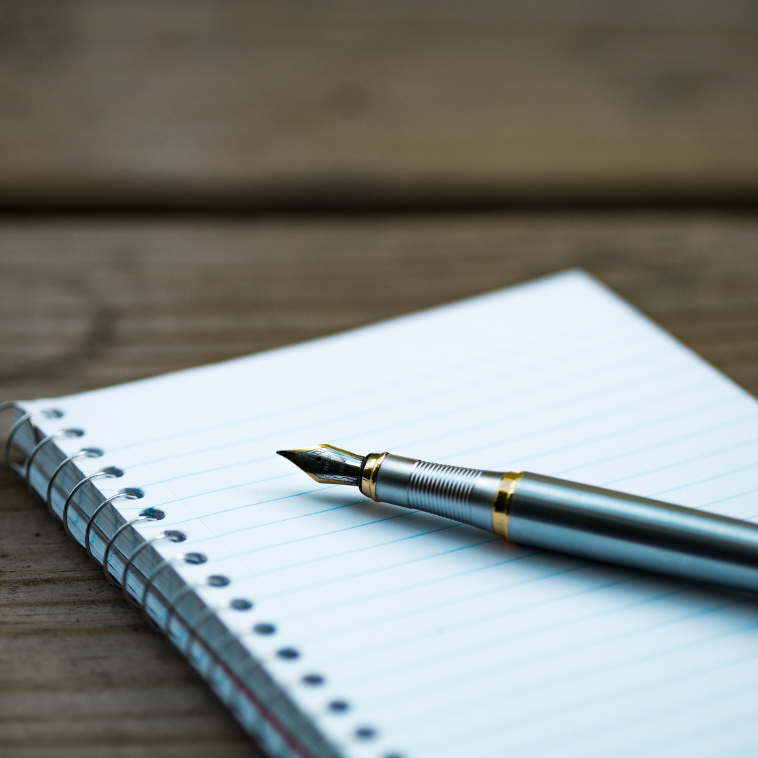 A fountain pen resting on an open notebook, representing the creative and personalized approach to author branding and marketing services.