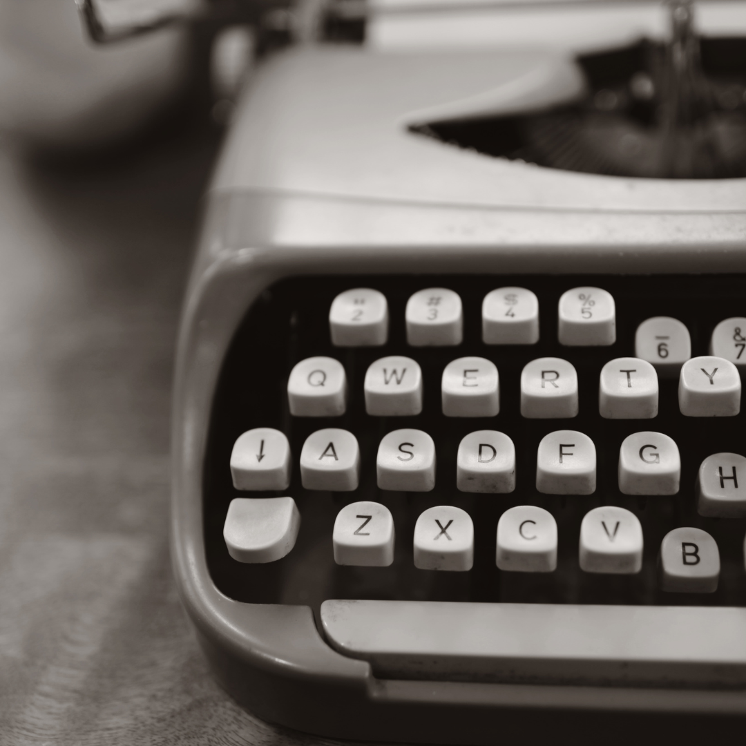 Close-up of a vintage typewriter in black and white, representing traditional storytelling and the foundational support offered by the service packages.