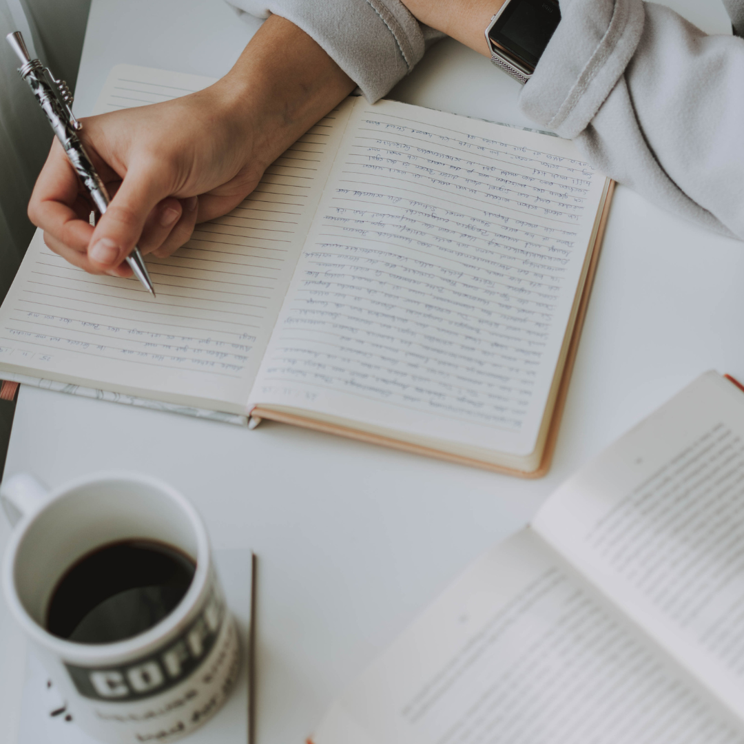 Writer planning content and author brand strategy in a notebook beside books and coffee.